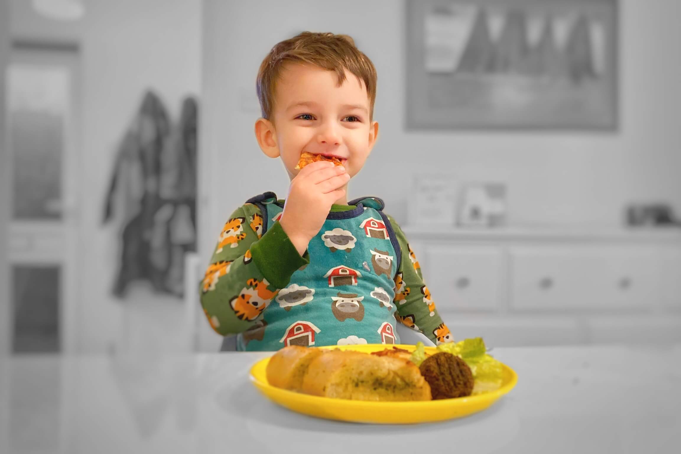 A happy toddler eating dinner at the table